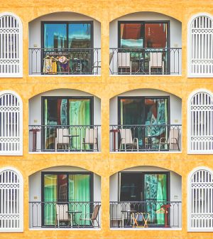 New vintage condo building blocks windows pattern | Upitravel Orange multi-story building with repeating arched balconies, white railings, and green-tinted windows.