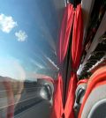 Viewing countryside while traveling with bus | Upitravel Bus interior with red curtains and red seats, window showing highway and hills outside.